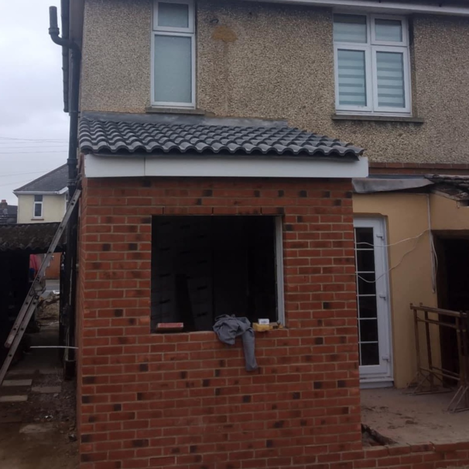 A new extension roof placed on a red brick installation with no windows. 